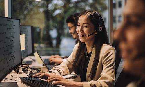 smiling woman at a computer talking on a headset